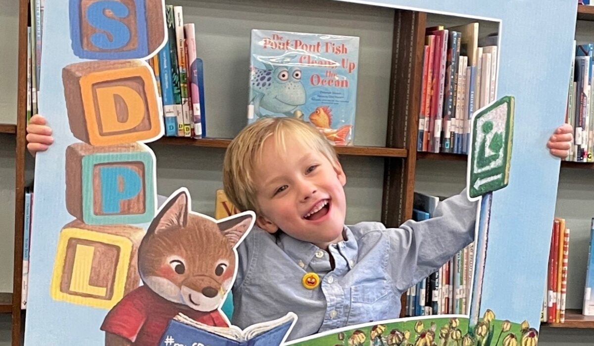 Boy smiles as he receives his first San Diego Public Library card.