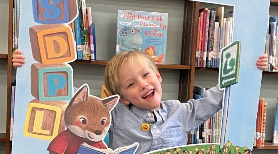 Boy smiles as he receives his first San Diego Public Library card.